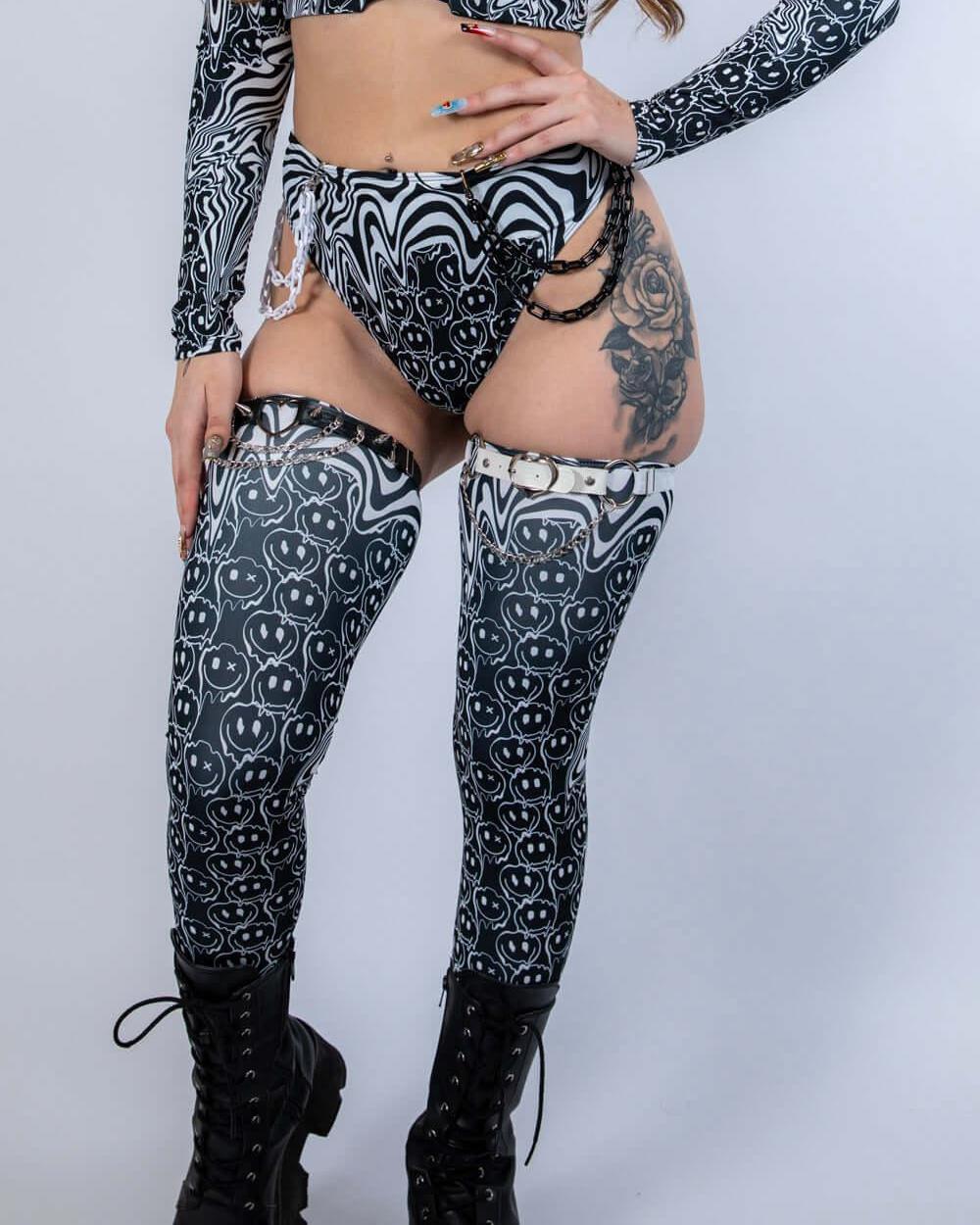 Model wearing Meltdown Leg Sleeves in a front-facing pose with matching ravewear, highlighting the melty smiley design and high-boot coverage.