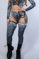Model wearing Meltdown Leg Sleeves in a front-facing pose with matching ravewear, highlighting the melty smiley design and high-boot coverage.