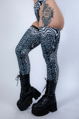 Model in Meltdown Leg Sleeves posing with one knee bent, showcasing the stretchy fit and bold festival-ready pattern.