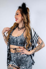 Model wearing the Meltdown Lush Top with one arm raised, showcasing the halter-style neckline and trippy smiley print.