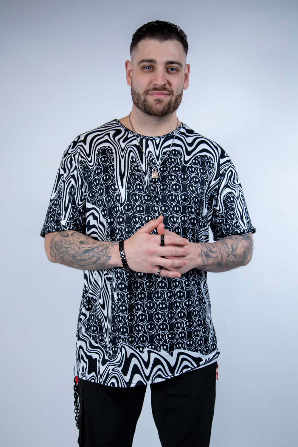 Model wearing the Meltdown Oversized Softee in a front-facing pose with hands clasped, showing off the relaxed fit and trippy smiley design.