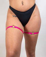 O-Ring leg garter set in pink with high-quality elastic, worn above a black bikini bottom, perfect for rave outfits.