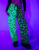 OG Batty 50/50 Lucy Pants - UV Green showcased under blacklight with bat silhouettes for rave outfits.