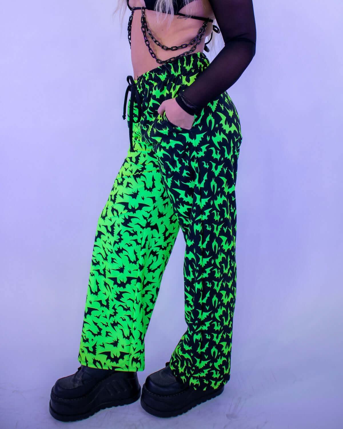 Model wearing OG Batty 50/50 Lucy Pants - UV Green with electric bat silhouettes, perfect for rave outfits.