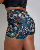 Woman wearing Poison High Waist Shorts with bold skull and mushroom print, perfect for rave outfits.