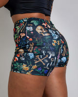 Woman wearing Poison High Waist Shorts with bold skull and mushroom print, perfect for rave outfits.