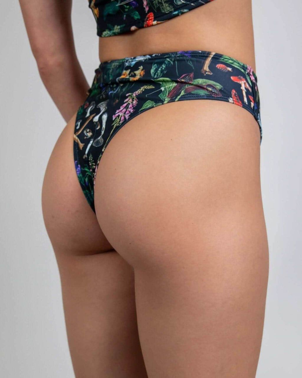 Model showcasing the Poison High Waisted Thong with bold skull and plant print, perfect for rave outfits.