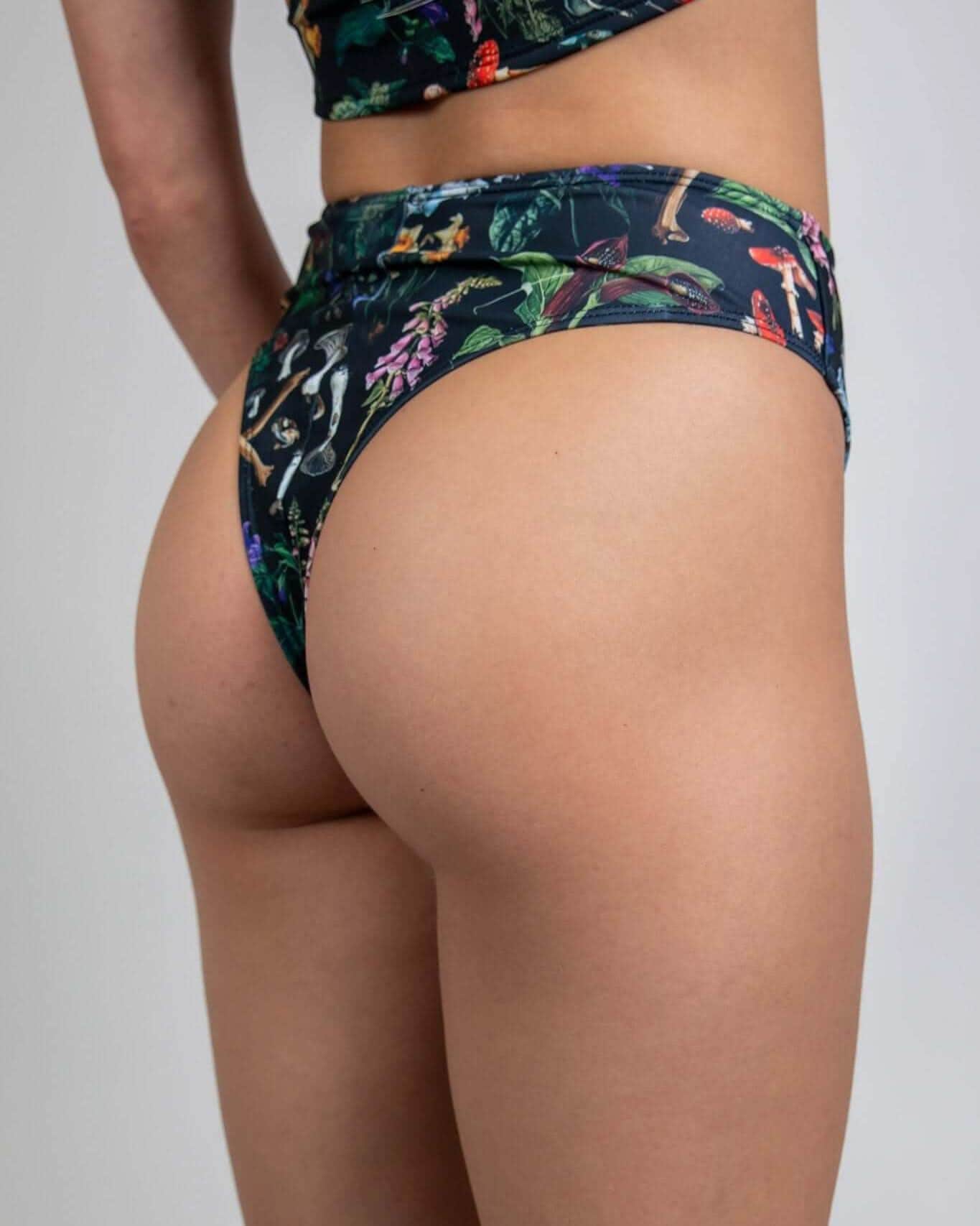 Model showcasing the Poison High Waisted Thong with bold skull and plant print, perfect for rave outfits.
