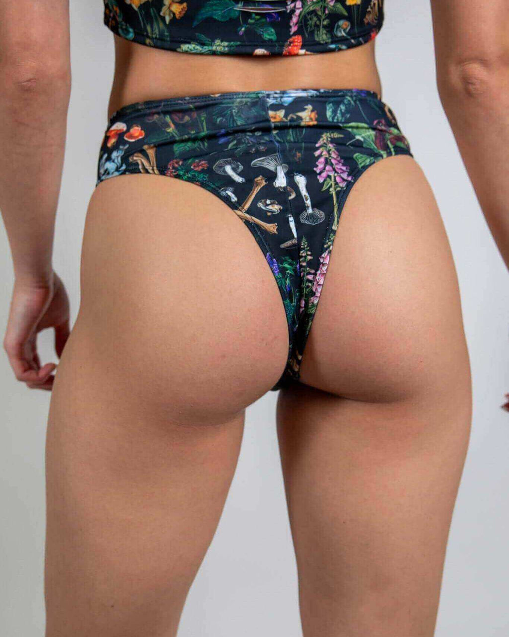 Poison High Waisted Thong with bold skull and mushroom prints, showcasing a high-rise fit and cheeky thong style for rave outfits.