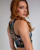 Model showcasing the back of the Poison Slit Crop Top with edgy slit details and vibrant skull and plant print.