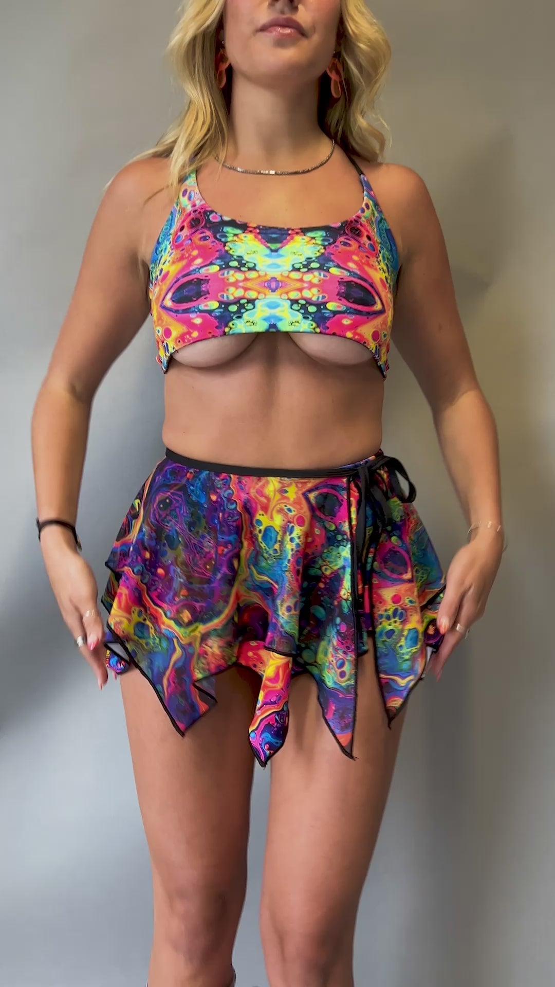 Video of Freedom Rave Wear set featuring a psychedelic lush top with unique cutouts and a matching flowy skirt. Perfect for vibrant festival looks