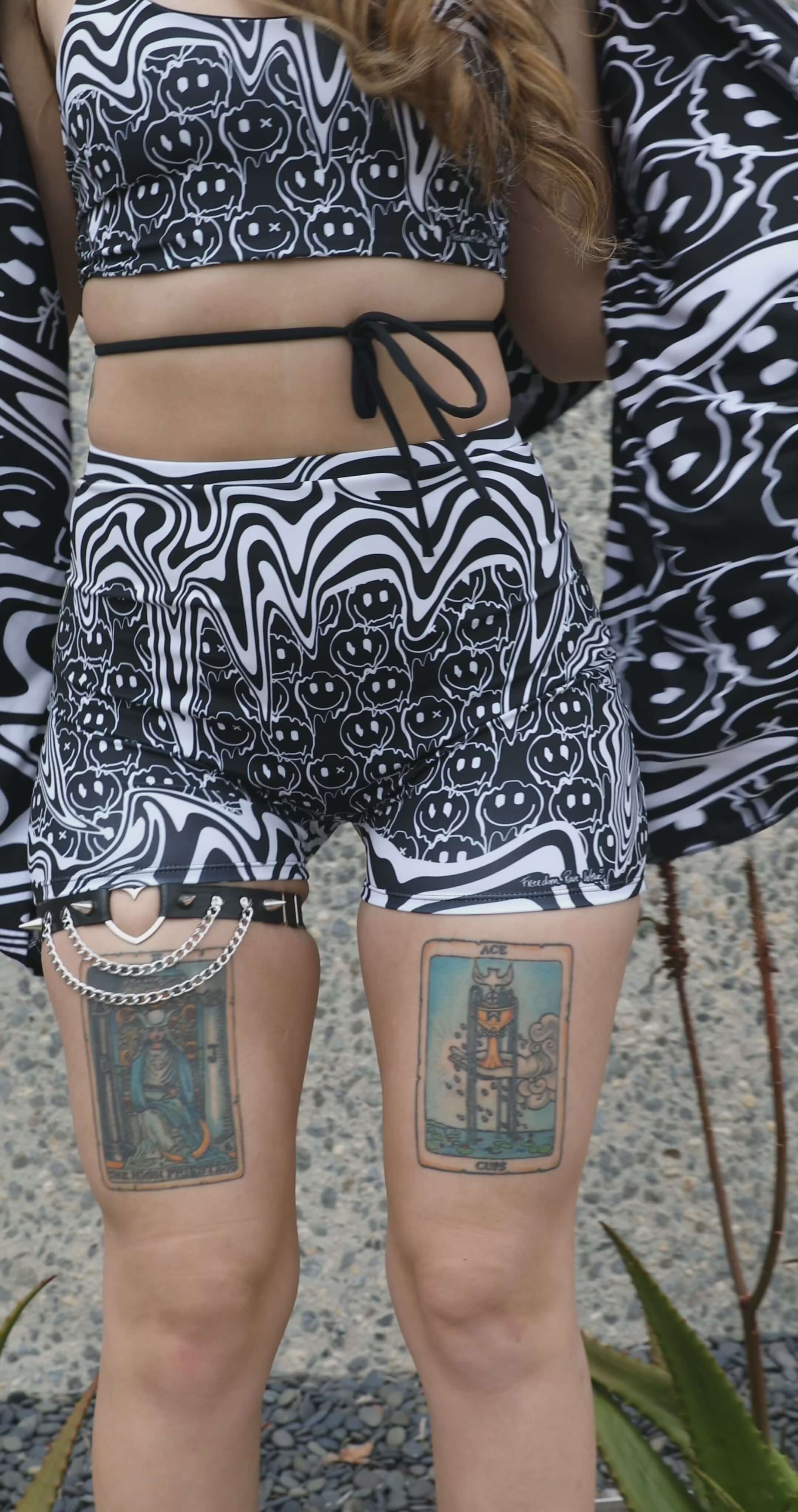 Model wearing Meltdown High Waist Shorts outdoors, styled with matching pieces to showcase the full melty smiley look.