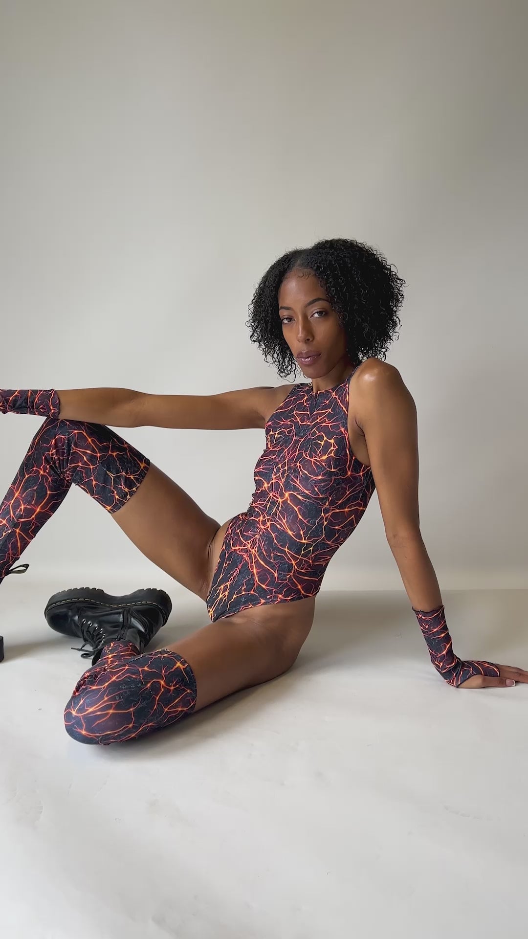 Video of model showcasing the front of a Freedom Rave Wear bodysuit with vivid lightning pattern, high-cut legs, and matching fingerless gloves.