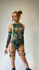 Video of model wearing Freedom Rave Wear's cutout bodysuit with a tropical dinosaur print, paired with arm sleeves and strappy leg accessories, perfect for rave adventures.