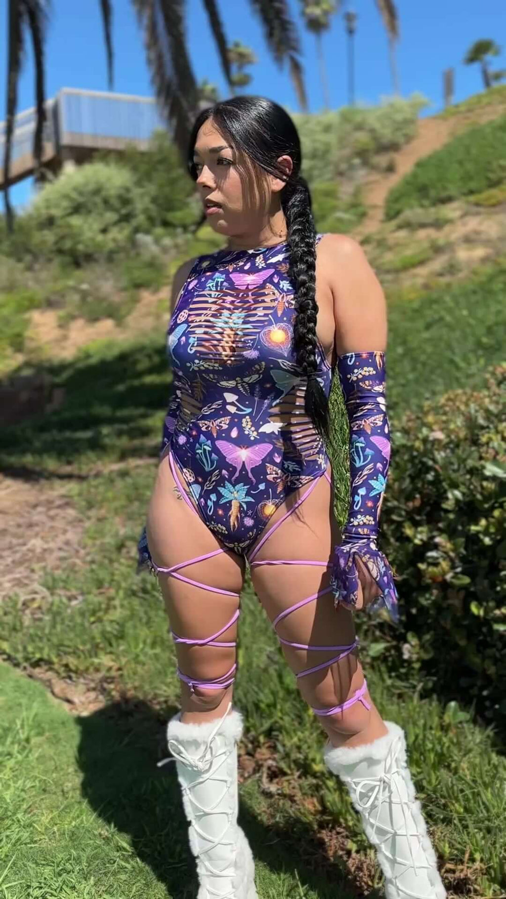 Lucent Slit Sideboob Bodysuit with Leg Straps showcased outdoors, featuring a colorful celestial design and edgy side cutouts.