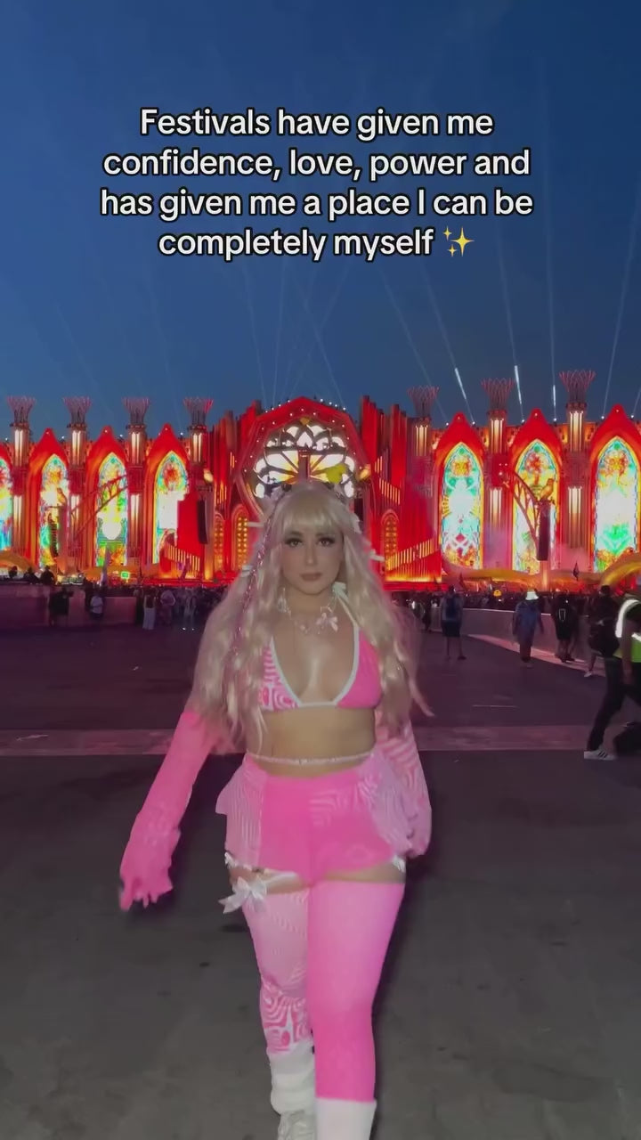 rave girl in neon pink and white rave outfit and matching accessories dances in front of main stage and edc las vegas music festival