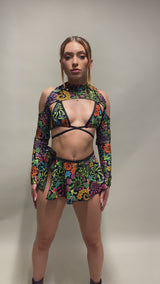 Rave Model flaunting Freedom Rave Wear's Psybloom Psychedelic floral bikini tie top, spectra sleeves, and swirl skirt. 