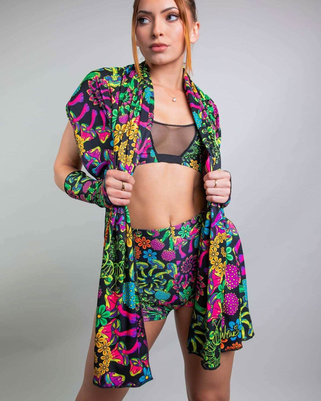 Model showcasing vibrant PsyBloom Festival outfit, featuring colorful scarf, bikini top, and shorts for rave fashion.