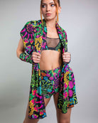 Model showcasing vibrant PsyBloom Festival outfit, featuring colorful scarf, bikini top, and shorts for rave fashion.