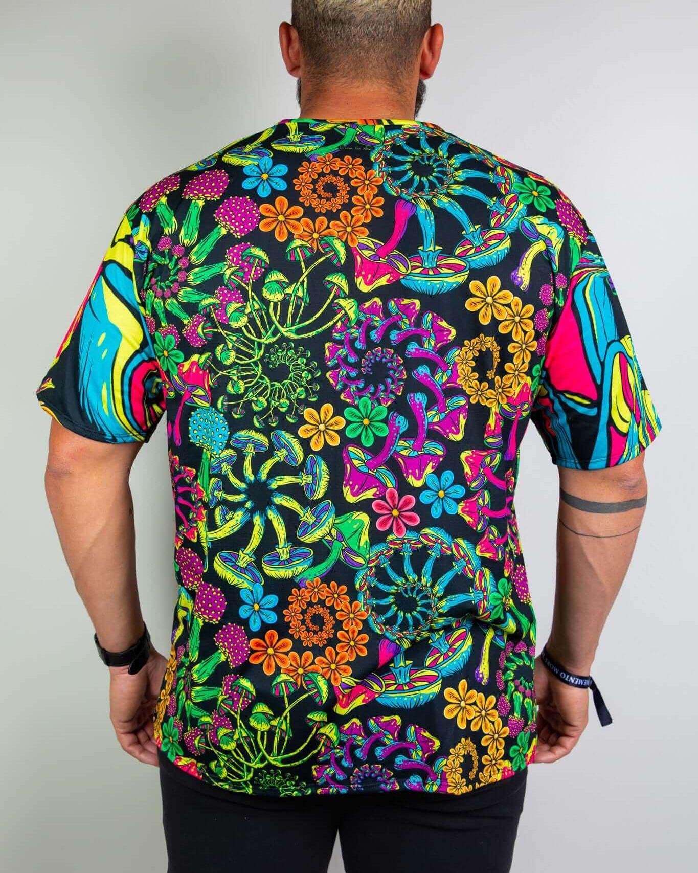 Back view of a man wearing the PsyBloom Oversized Tee with colorful mushroom and floral print, ideal for rave outfits.