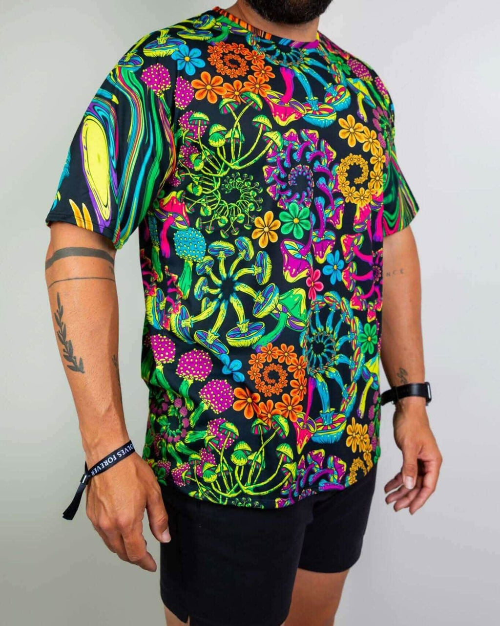 Man in vibrant PsyBloom Oversized Tee featuring a colorful mushroom and flower print, perfect for rave outfits.