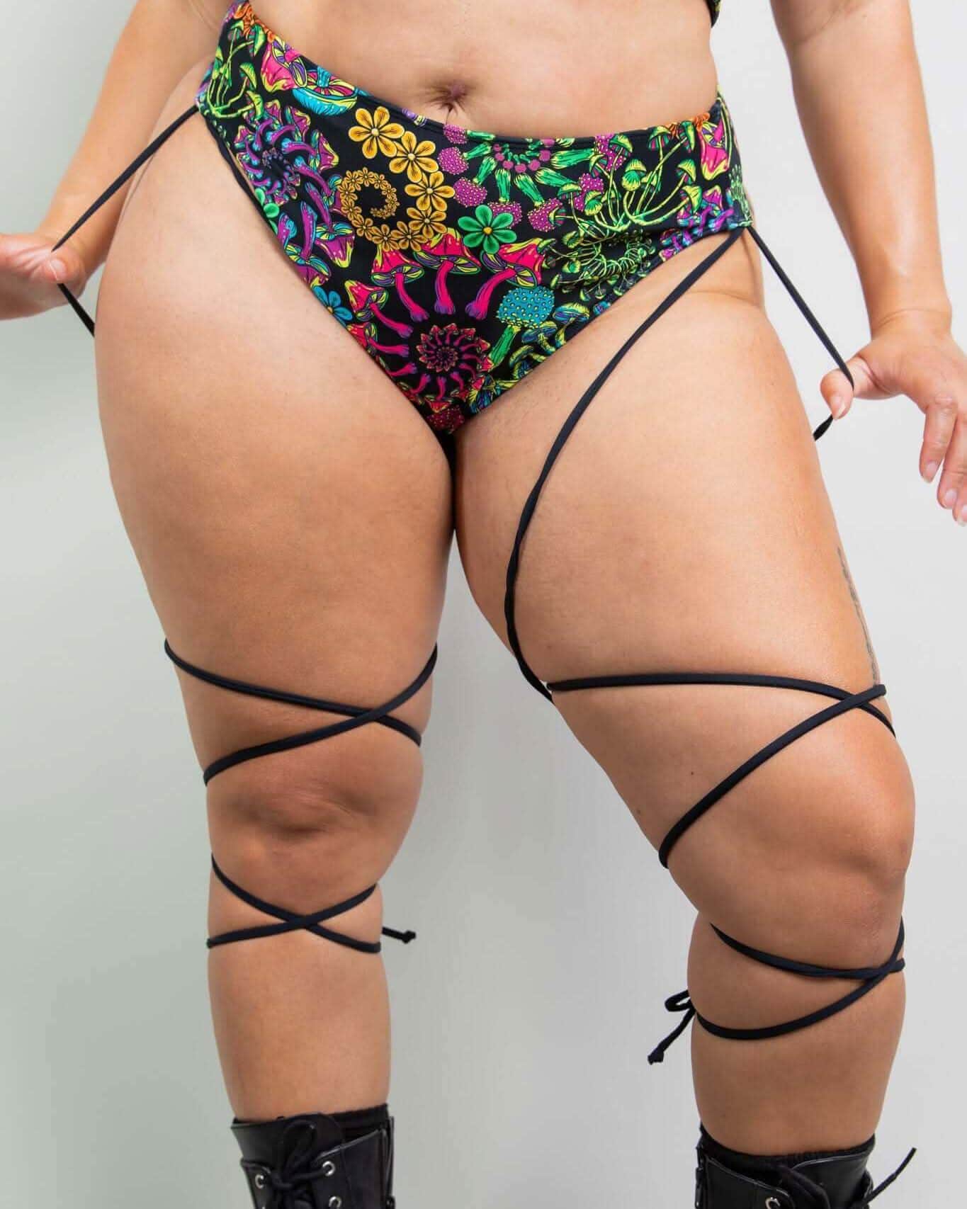 PsyBloom colorful floral rave pants with black strappy leg details modeled from front view