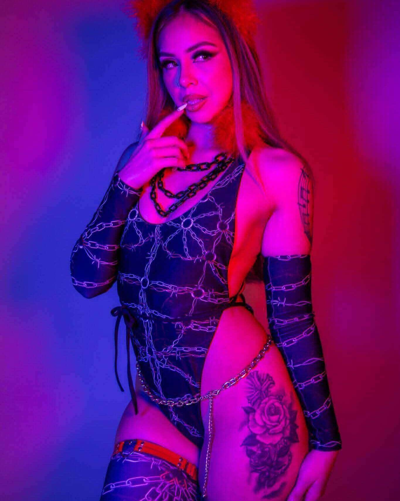 Model showcasing the Purgatory Temptation Cheeky One Piece, featuring chain graphics and bold styling against vibrant background.