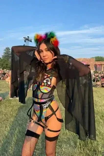 Model wearing black mesh rave arm sleeves with bell design at outdoor festival setting