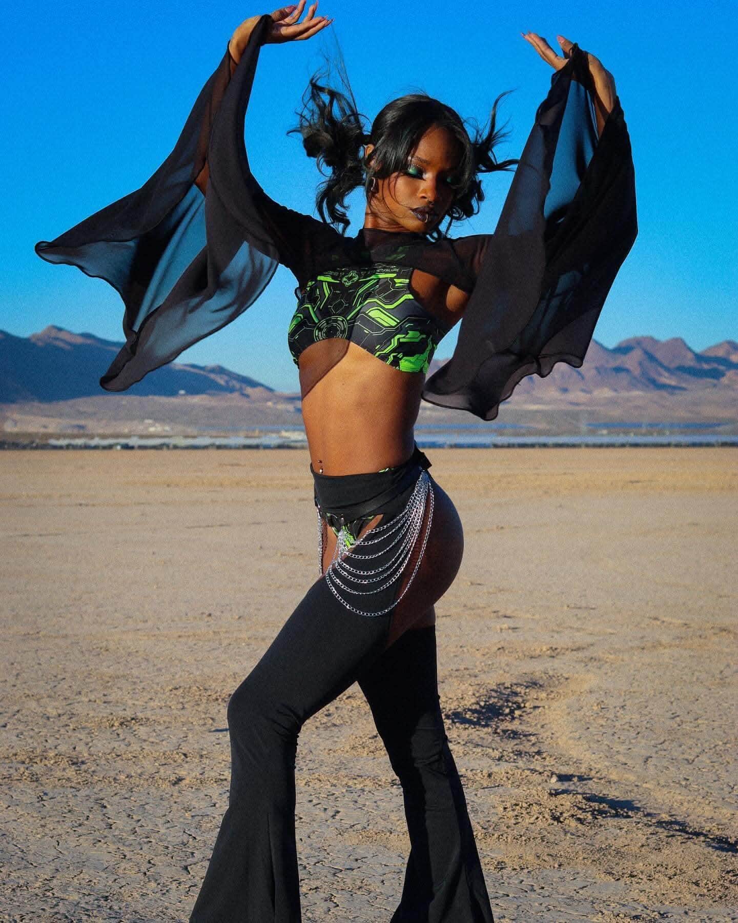 Black mesh rave arm sleeves with dramatic bell design worn by model dancing in desert festival setting