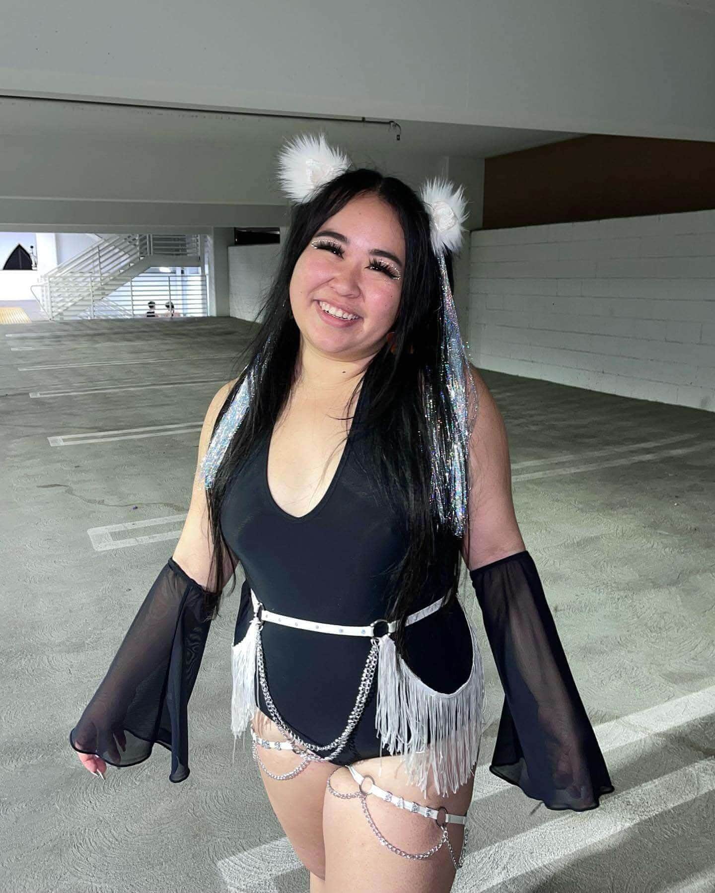 Model wearing black mesh flare rave arm sleeves with festival outfit in parking garage lifestyle shot