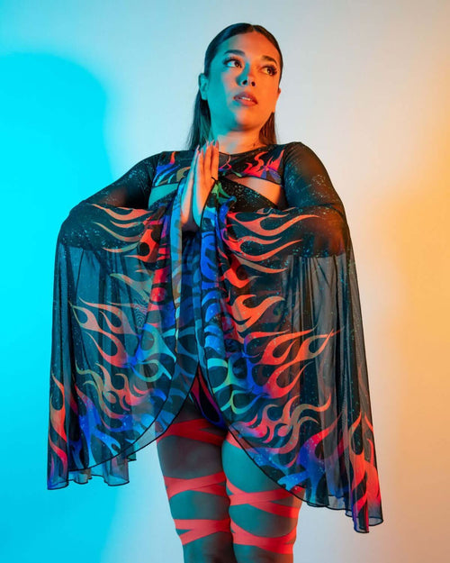 Model wearing Blaze flame pattern rave arm sleeves with flowing bell design in dramatic festival lighting