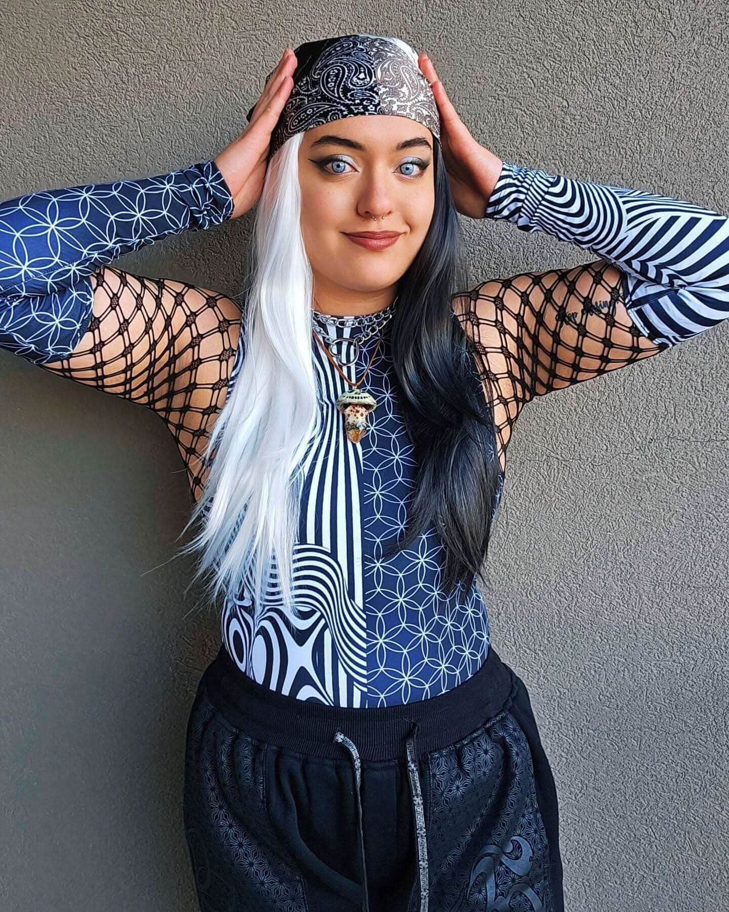 Model wearing Duality rave arm sleeves with blue geometric patterns and black fishnet overlay for festival outfit styling