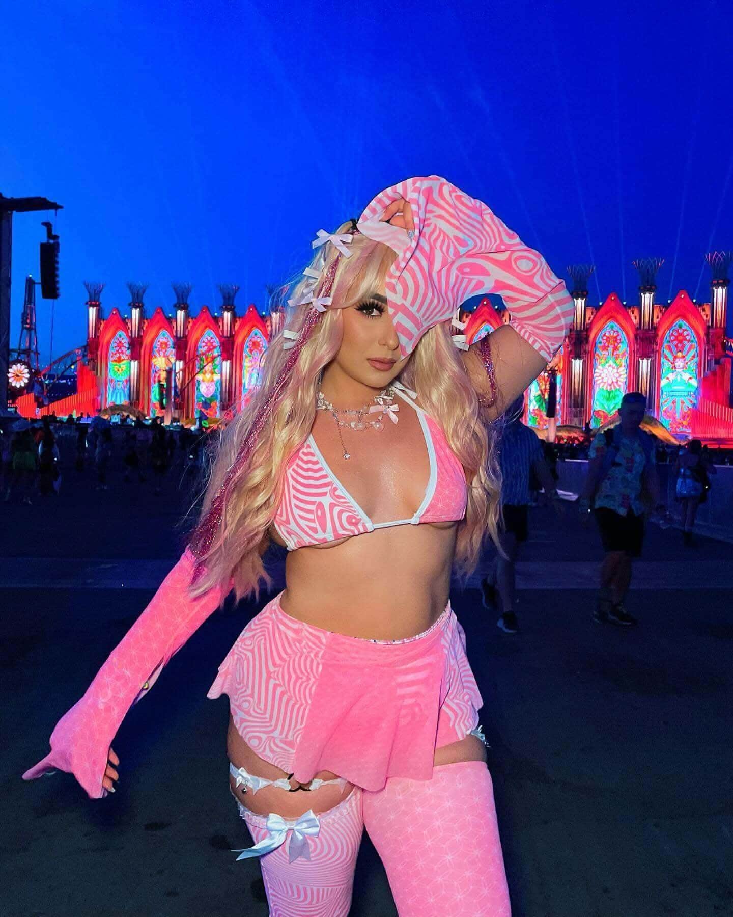 Model wearing pink Electricity Metamorphosis rave arm sleeves with matching festival outfit at EDM event