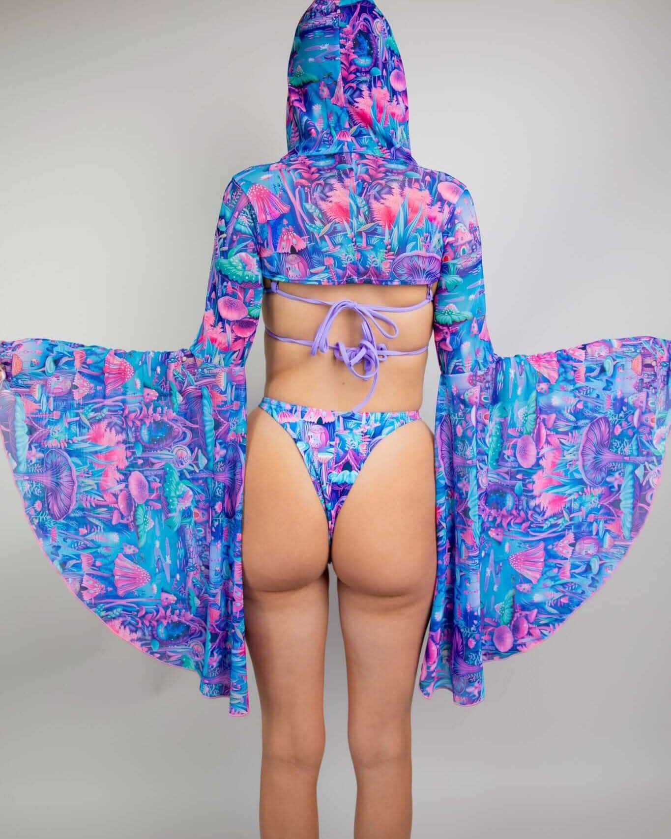 Back view of model in Fairycore rave arm sleeves with dramatic bell sleeves in blue pink purple print