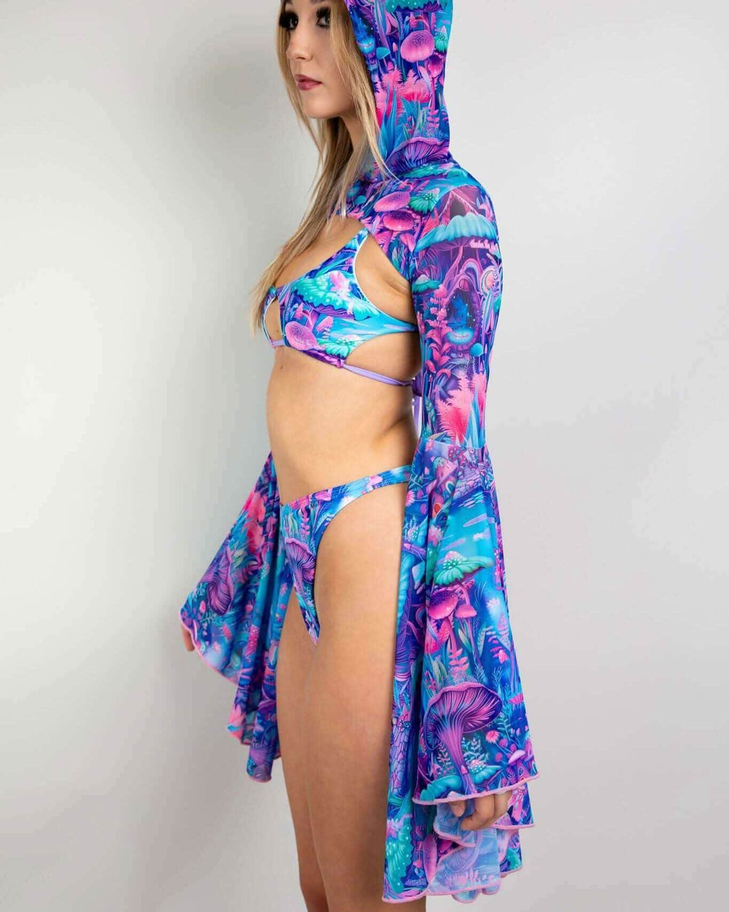 Side view of model wearing Fairycore rave arm sleeves with hooded bell design in blue pink purple print