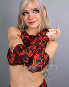 Model wearing red geometric Labyrinth rave arm sleeves in crossed arms pose for festival outfit styling