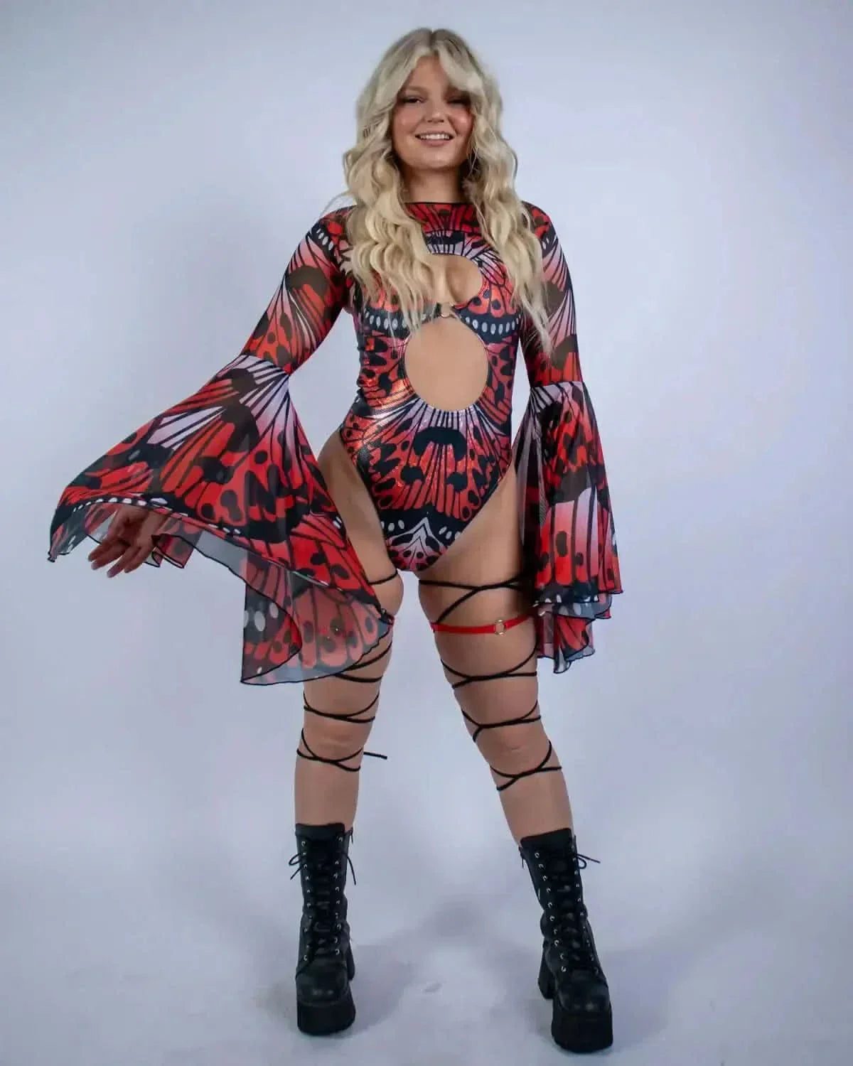 Blonde model showcasing Lacewing rave arm sleeves with dramatic bell sleeves in red and black mesh for festival outfit