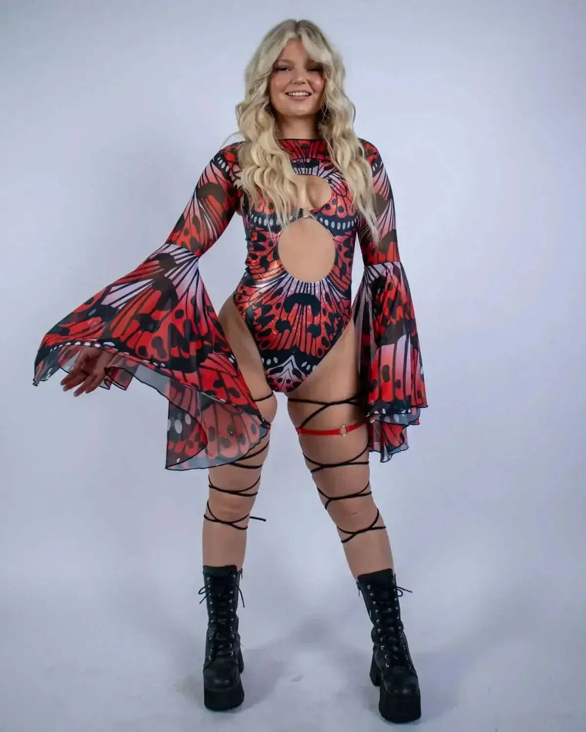Blonde model showcasing Lacewing rave arm sleeves with dramatic bell sleeves in red and black mesh for festival outfit
