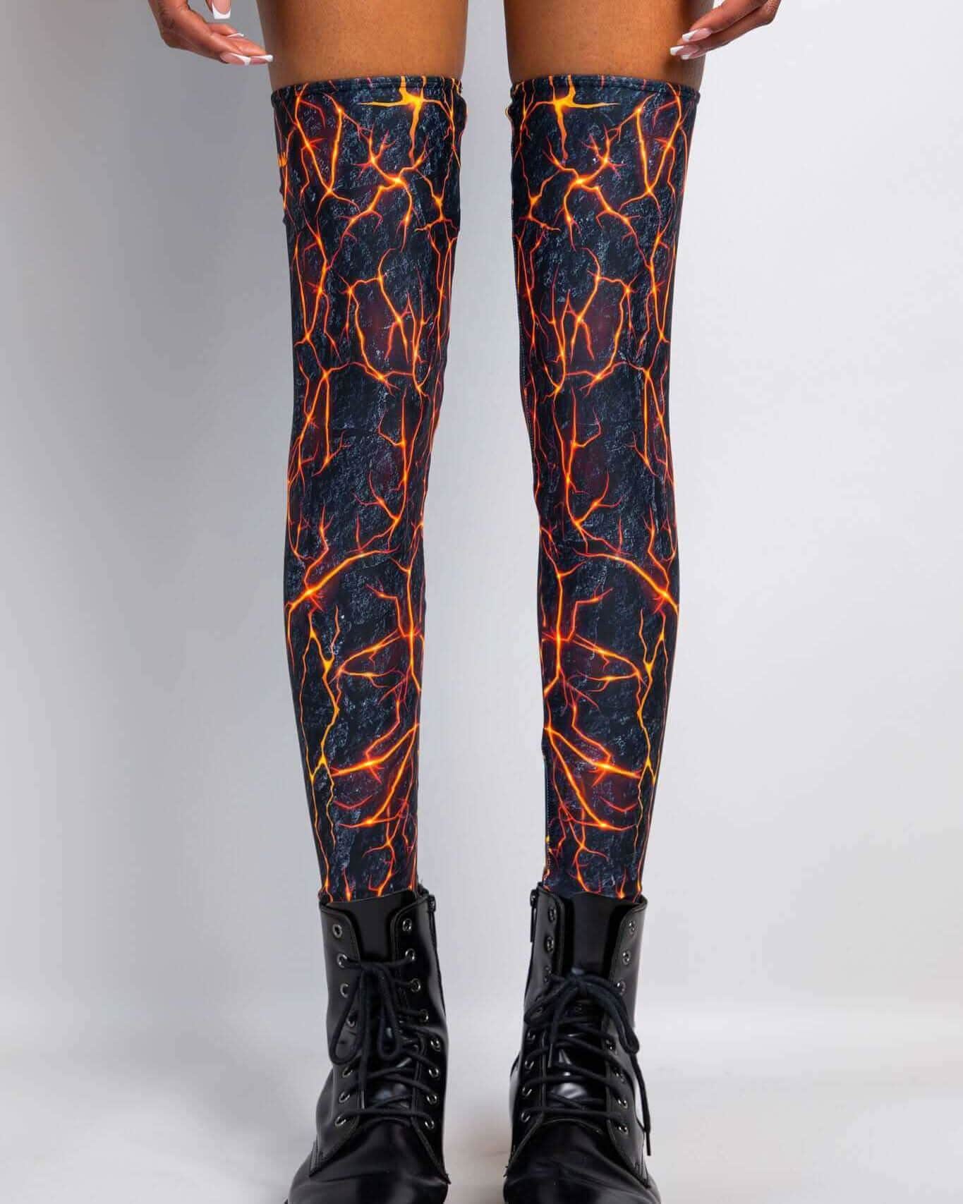 Magma rave arm sleeves with fiery orange lava pattern on black base, thigh-high festival leg wear front view