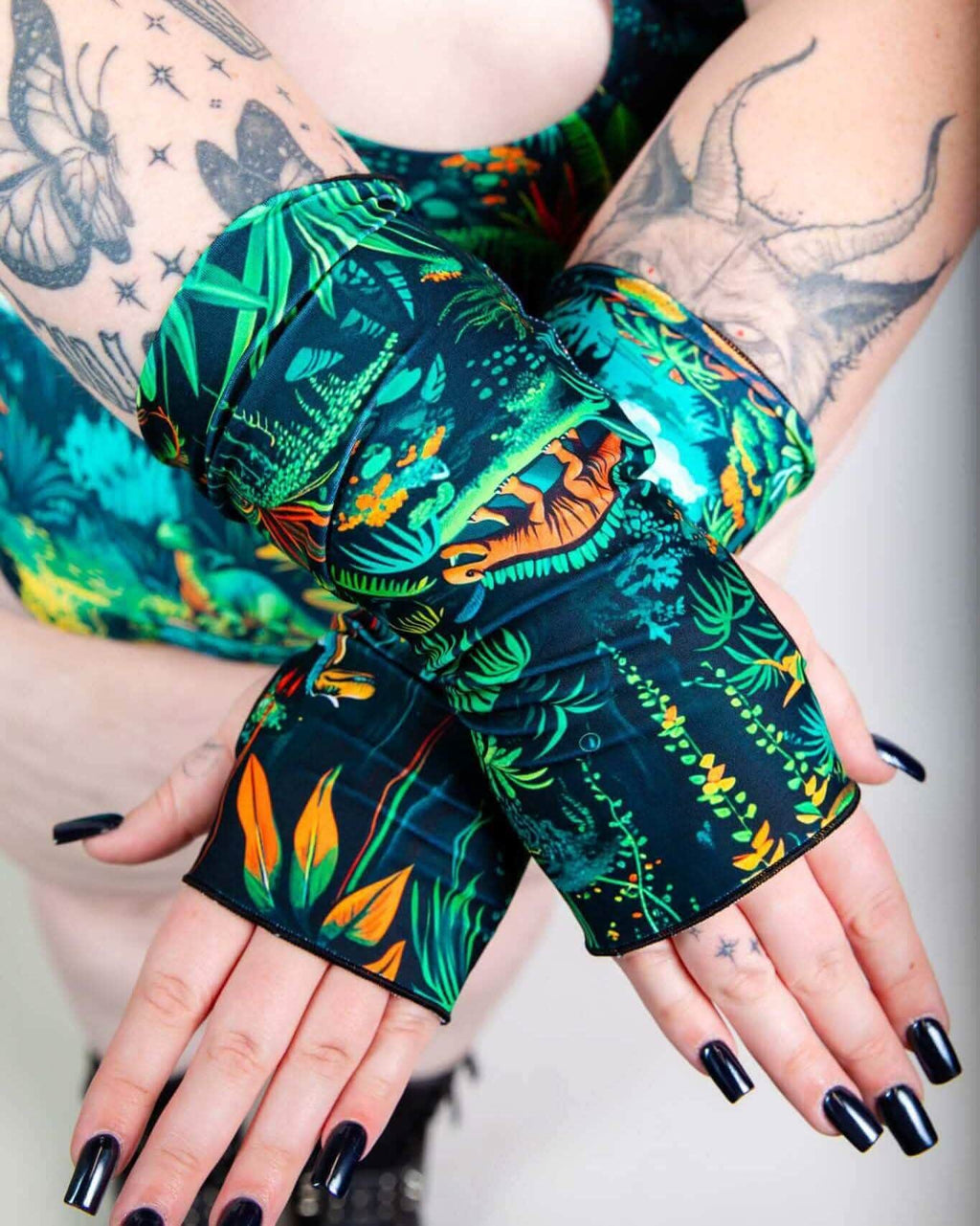 Mesozoic rave arm sleeves with tropical jungle print displayed on tattooed model's hands palm-forward