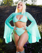 Model wearing mint green mesh rave arm sleeves with flowing bell sleeves in outdoor festival outfit pose