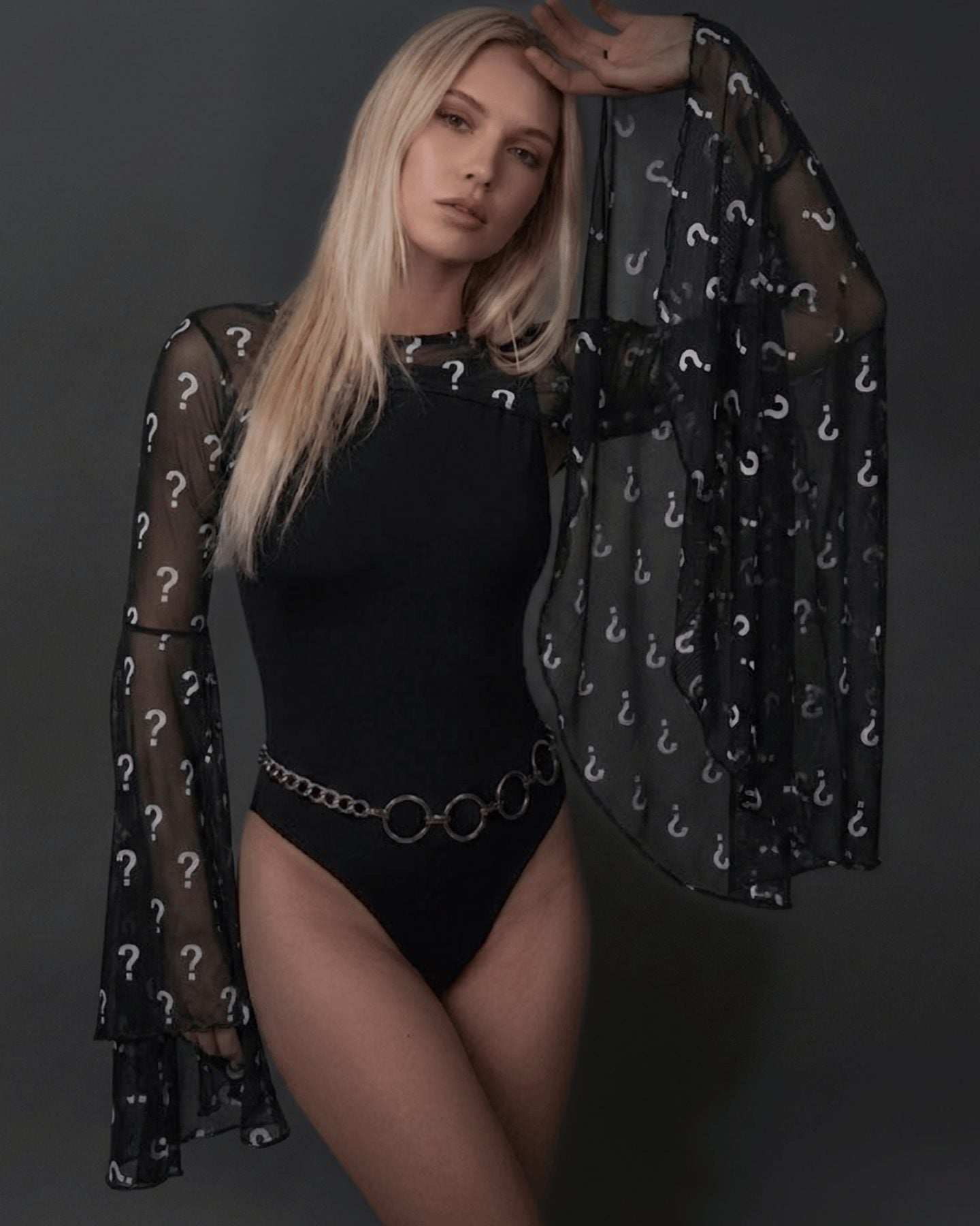 Model wearing mystery rave arm sleeves with question mark pattern over black bodysuit festival outfit front view