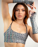Model wearing black white geometric rave arm sleeves with matching crop top in raised arms pose