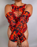 Model wearing red dragon print rave arm sleeves with strategic slits, seated pose against white background