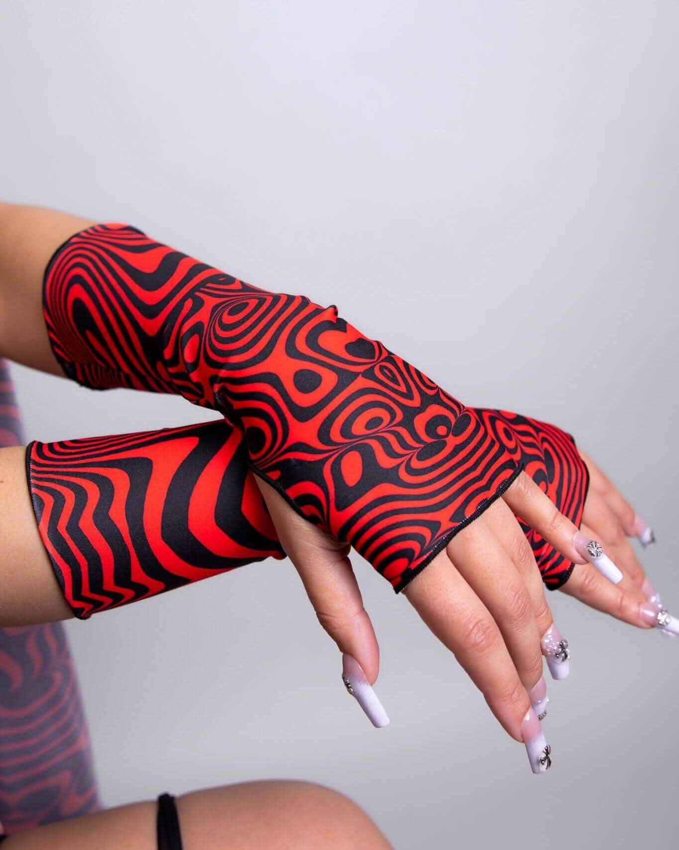 Red Void rave arm sleeves with swirling black patterns on crossed arms for festival outfit styling