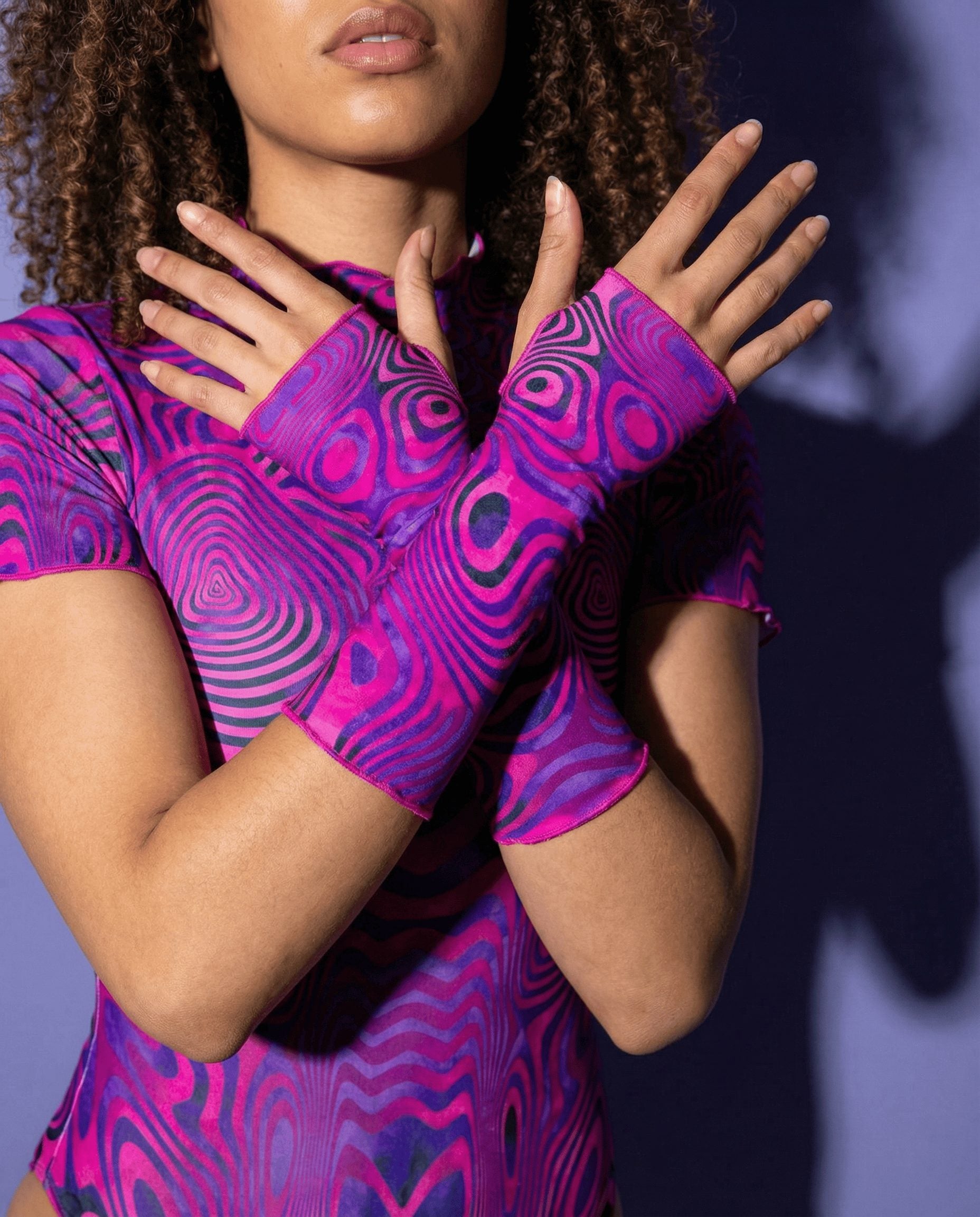 Model showcasing Vanish rave arm sleeves with pink purple swirls in defensive hand pose