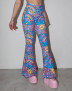 Groovy Bell Bottoms in a psychedelic blue and purple pattern, featuring smiley faces and rainbows, worn by a person facing front, ideal for festival fashion.