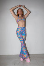 Front view of Groovy Bell Bottoms and matching top on a model, showcasing the psychedelic rave pattern with smiley faces and rainbows.