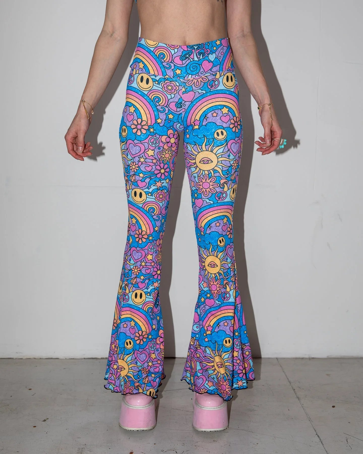 Groovy Bell Bottoms in a psychedelic pattern featuring smiley faces and rainbows, perfect for rave festivals