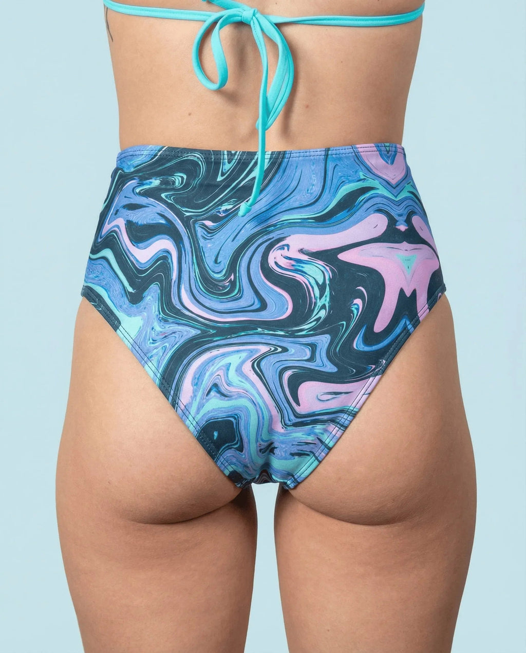 Glacial High Waisted Bikini Bottoms from the back, featuring a unique blue, teal, and lilac marbled rave pattern.
